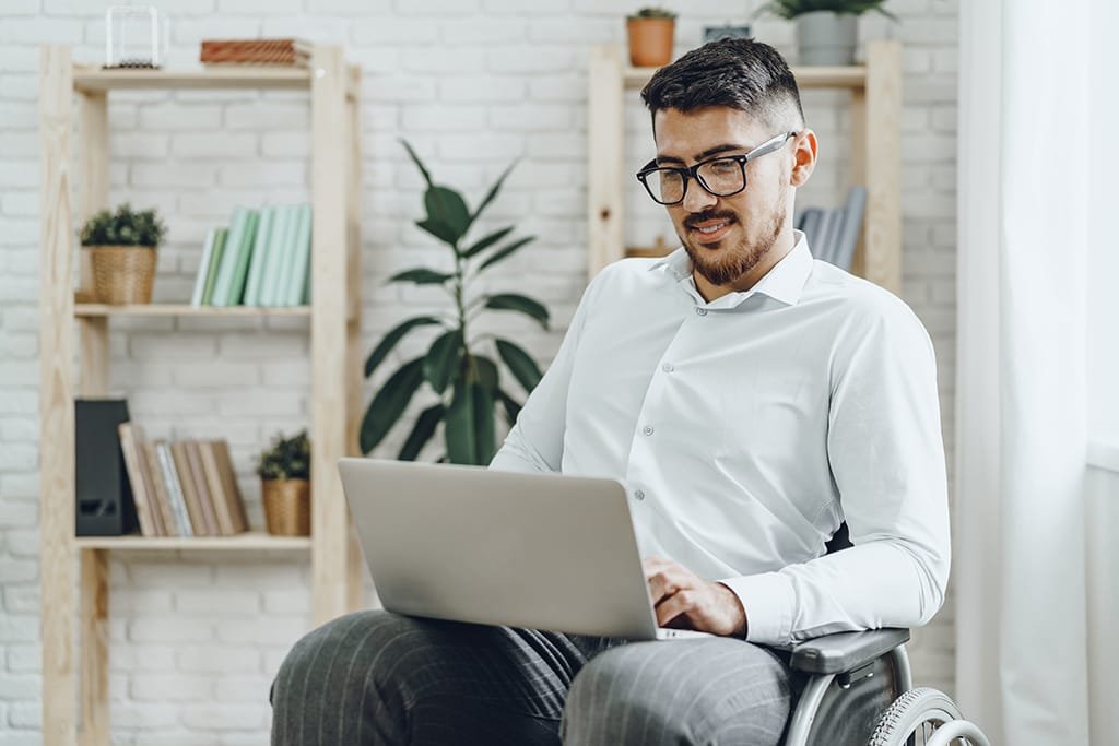 Businessman sitting in wheelchair and using laptop